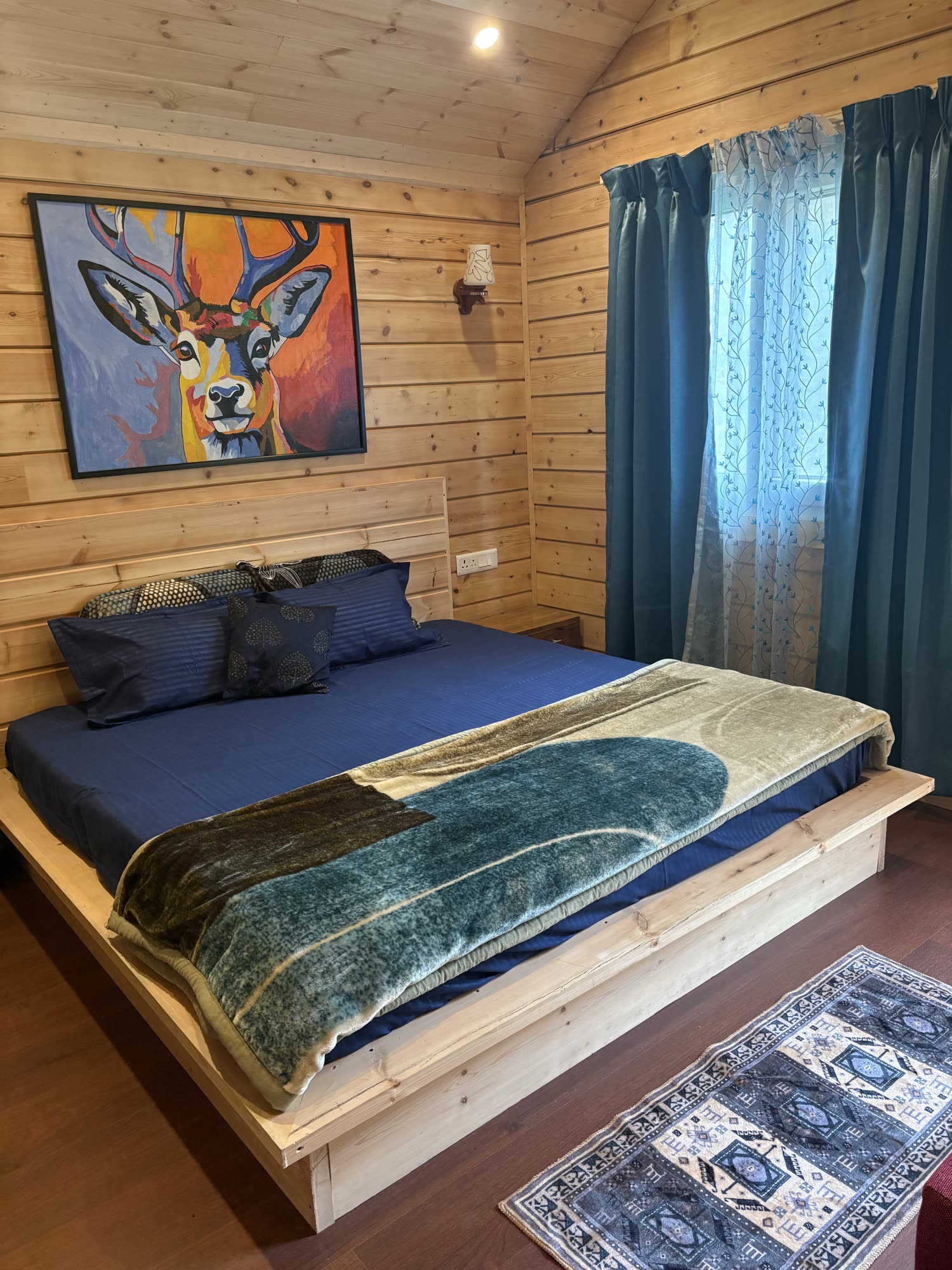 Second bedroom with a king-size bed, blue bedding and a vibrant deer painting